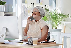 Young African American businesswoman sitting alone in an office and talking to clients with a cellphone. Smiling