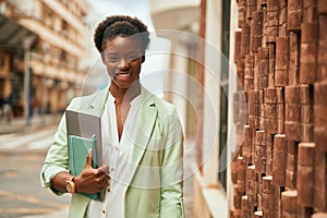 Young african american businesswoman smiling happy holding laptop at the city