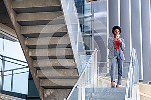 Young African-American businesswoman texting on the phone in a business building