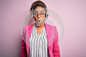 Young african american call center agent girl wearing glasses working using headset afraid and shocked with surprise expression,