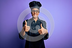 Young african american chef girl wearing cooker uniform and hat over purple background success sign doing positive gesture with