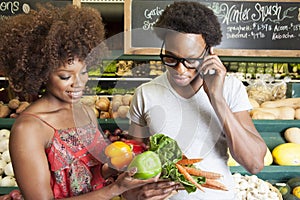 Young African American couple buying vegetables at supermarket