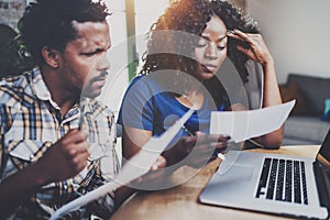 Young African american couple checking bills together at the wooden table.Young black man and his girlfriend using