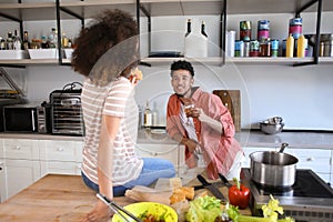 Young African-American couple eating and drinking in kitchen