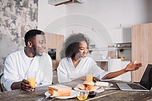 Young african american couple sitting at table with laptop