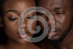 young african american couple with water drops on faces posing with closed eyes