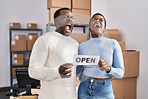 Young african american couple working at small business ecommerce angry and mad screaming frustrated and furious, shouting with