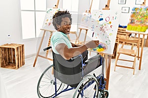 Young african american disabled artist man sitting on wheelchair drawing at art studio