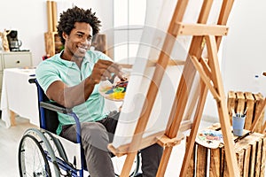 Young african american disabled artist man sitting on wheelchair drawing at art studio