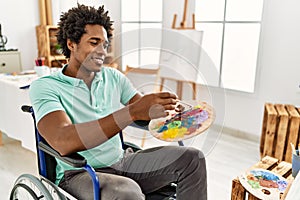 Young african american disabled artist man sitting on wheelchair drawing at art studio