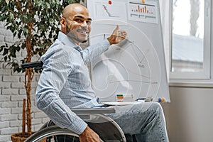 Young african american disabled man in a wheelchair makes presentation at office on whiteboard