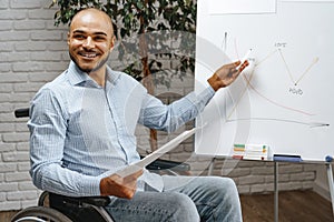 Young african american disabled man in a wheelchair makes presentation at office on whiteboard