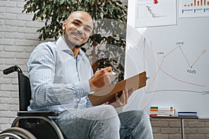 Young african american disabled man in a wheelchair makes presentation at office on whiteboard