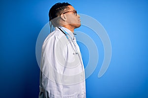 Young african american doctor man with dreadlocks wearing stethoscope and glasses looking to side, relax profile pose with natural