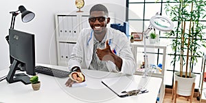Young african american doctor man holding anatomical model of female uterus with fetus at the clinic smiling happy and positive,