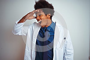 Young african american doctor man wearing coat standing over isolated white background very happy and smiling looking far away