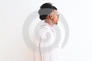 Young african american doctor man wearing pink stethoscope over isolated white background looking to side, relax profile pose with