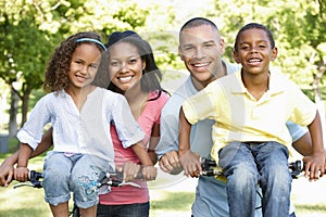 Young African American Family Cycling In Park