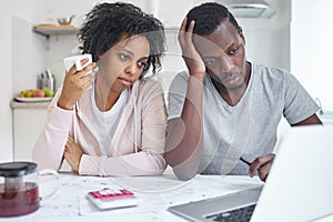 Young african american family reviewing their finances using online bank application