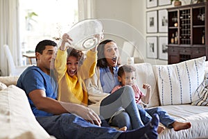 Young African American  family sitting together on the sofa in their living room watching a scary movie