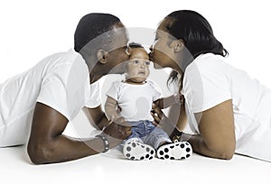 Young African American family in the studio with baby toddler son giving kiss