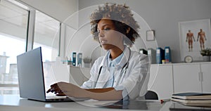 Young African-American female doctor in office working on laptop