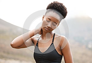 Young african american female suffering from neck pain while working out outside in nature. Unhappy young woman holding