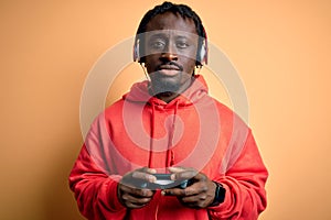 Young african american gamer man playing video game using joystick and headphones with a confident expression on smart face