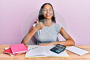 Young african american girl accountant working at the office doing happy thumbs up gesture with hand