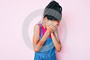 Young african american girl child with braids wearing casual clothes over pink background with sad expression covering face with