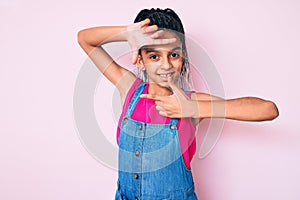Young african american girl child with braids wearing casual clothes over pink background smiling making frame with hands and
