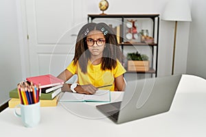 Young african american girl doing homework at home skeptic and nervous, frowning upset because of problem