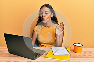 Young african american girl doing video call waving to laptop looking at the camera blowing a kiss being lovely and sexy