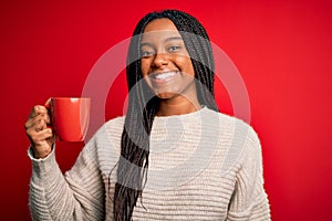 Young african american girl drinking a coffee cup over red isolated background with a happy face standing and smiling with a