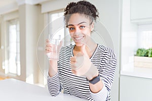 Young african american girl drinking a fresh glass of water happy with big smile doing ok sign, thumb up with fingers, excellent