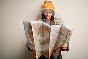 Young african american girl going on vacation holding turist city map over isolated background with a confident expression on