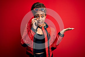Young african american girl having conversation talking on the smartphone over red background very happy and excited, winner