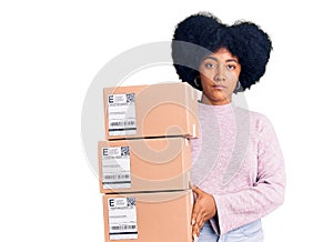 Young african american girl holding delivery package thinking attitude and sober expression looking self confident
