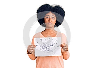 Young african american girl holding scribble draw thinking attitude and sober expression looking self confident