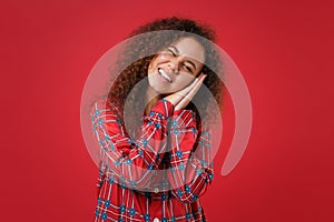 Young african american girl in pajamas homewear posing resting at home isolated on red background in studio. Relax good