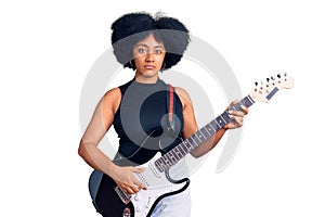 Young african american girl playing electric guitar thinking attitude and sober expression looking self confident