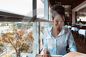 Young African American girl in restaurant with menu