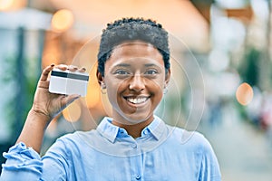 Young african american girl smiling happy holding credit card at the city