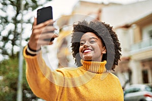 Young african american girl smiling happy making selfie by the smartphone at the city