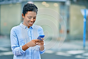 Young african american girl smiling happy using smartphone at the city