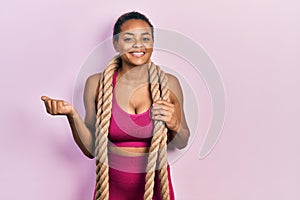 Young african american girl training with battle rope screaming proud, celebrating victory and success very excited with raised
