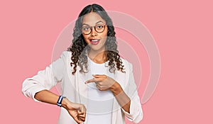 Young african american girl wearing business clothes in hurry pointing to watch time, impatience, upset and angry for deadline