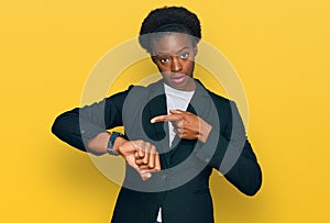 Young african american girl wearing business clothes in hurry pointing to watch time, impatience, upset and angry for deadline