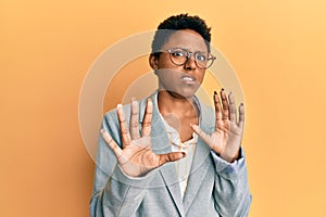 Young african american girl wearing business jacket and glasses afraid and terrified with fear expression stop gesture with hands,