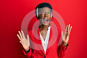 Young african american girl wearing call center agent headset celebrating mad and crazy for success with arms raised and closed